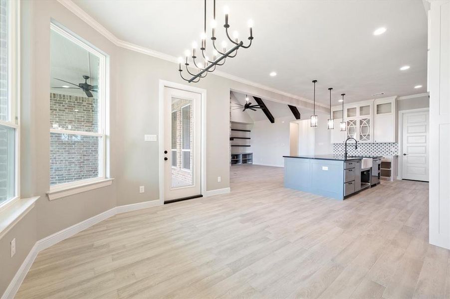 Kitchen featuring ceiling fan with notable chandelier, light hardwood / wood-style flooring, hanging light fixtures, and a center island with sink