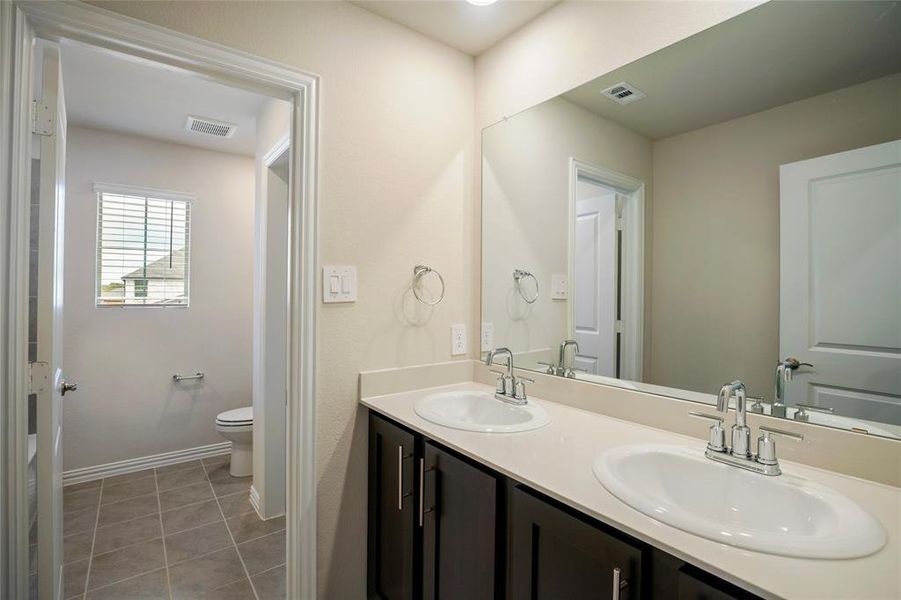 Bathroom featuring tile patterned flooring, double sink vanity, and toilet