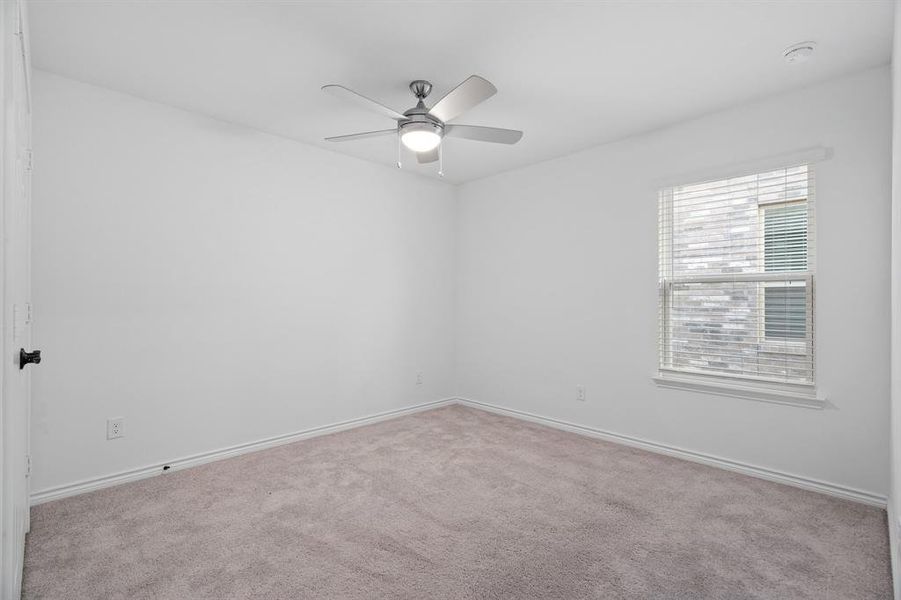 Empty room with ceiling fan and light carpet