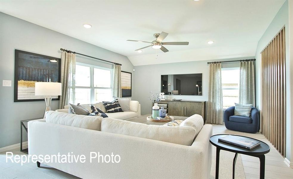 Living room with a wealth of natural light, ceiling fan, hardwood / wood-style flooring, and lofted ceiling