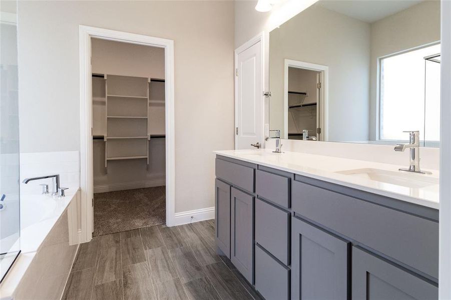 Bathroom with hardwood / wood-style floors, vanity, and tiled tub