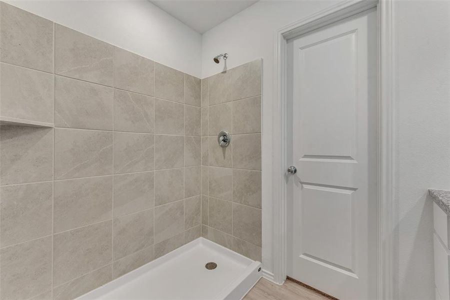 Bathroom with hardwood / wood-style flooring and tiled shower