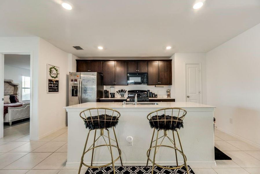 Kitchen with black appliances, a kitchen bar, an island with sink, and sink