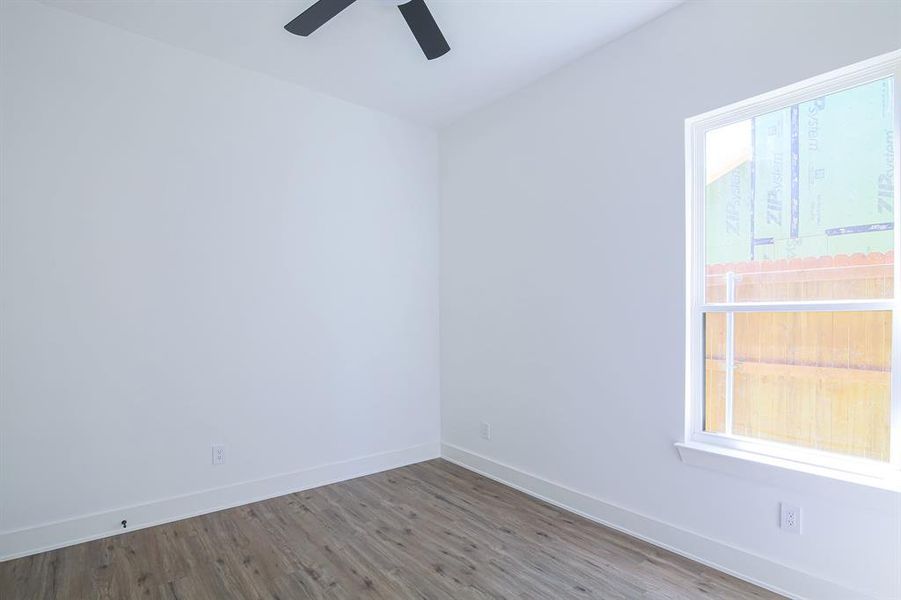 Empty room with hardwood / wood-style flooring, ceiling fan, and plenty of natural light