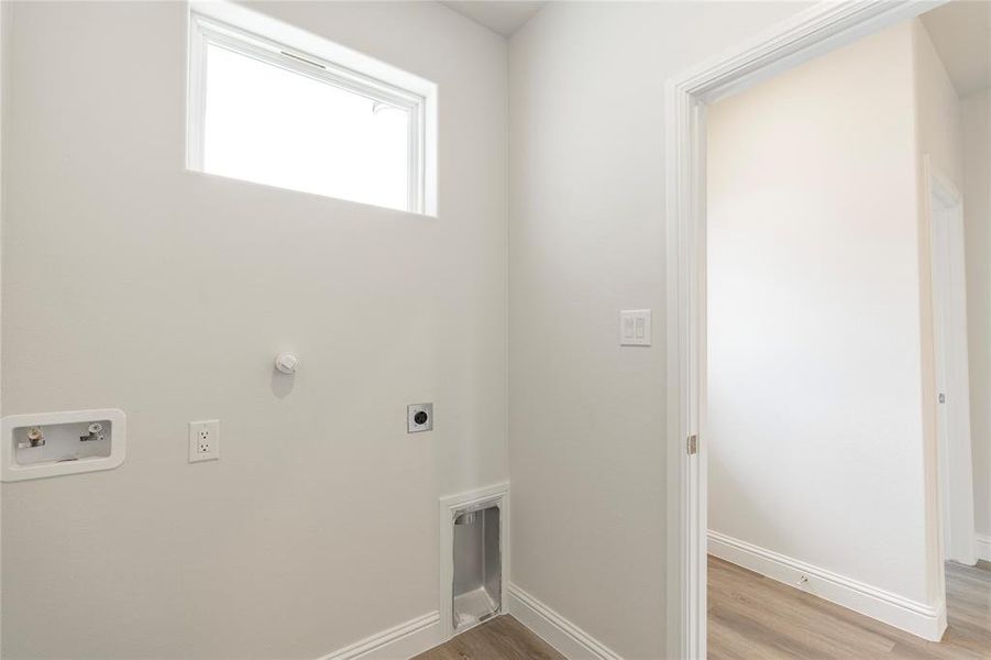 Clothes washing area with light wood-type flooring, hookup for a washing machine, and electric dryer hookup