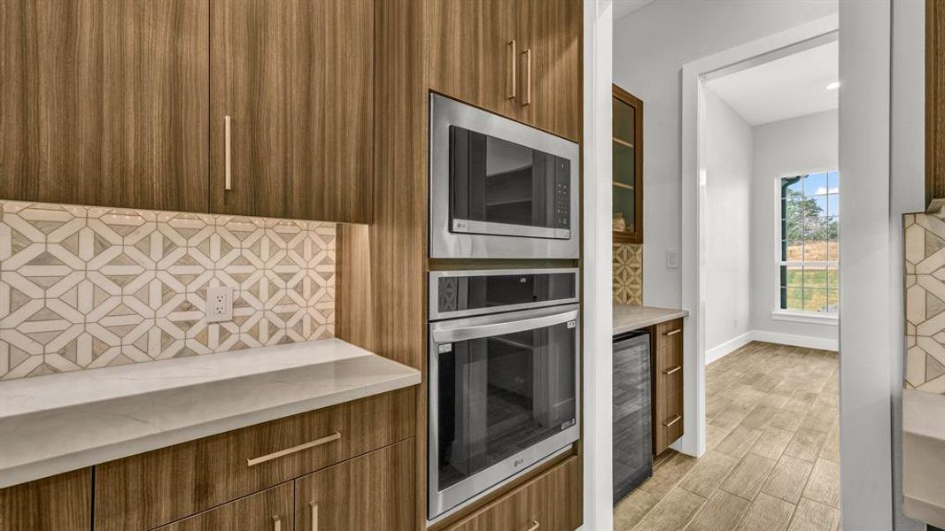 Kitchen with an island with sink, light wood-type flooring, stainless steel dishwasher, sink, and a fireplace