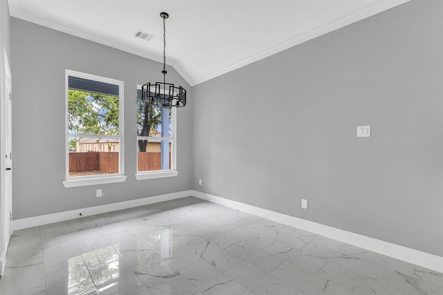 Unfurnished dining area with ornamental molding, vaulted ceiling, and an inviting chandelier