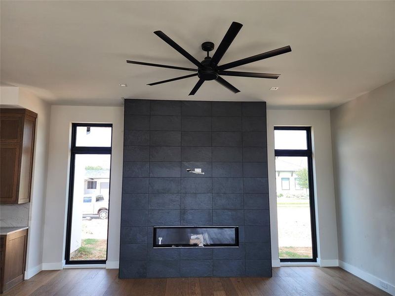 Unfurnished living room with a tiled fireplace, hardwood / wood-style floors, and a wealth of natural light