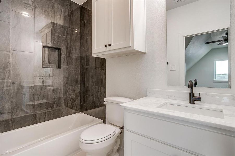 Full bathroom featuring vanity, ceiling fan, toilet, and tiled shower / bath