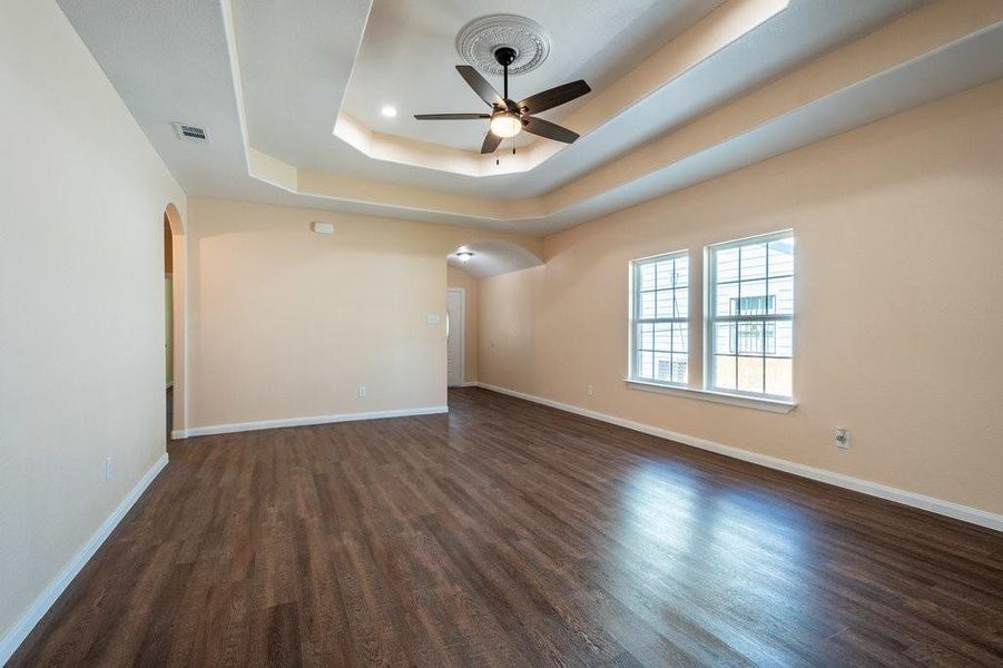 Spare room featuring dark wood-type flooring, a raised ceiling, and ceiling fan