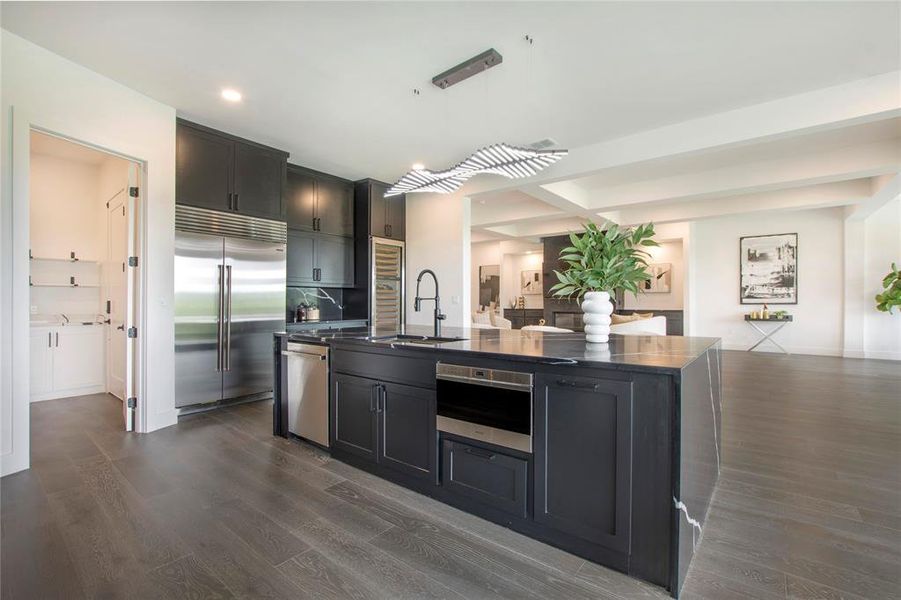 Kitchen featuring an island with sink, sink, appliances with stainless steel finishes, and dark hardwood / wood-style flooring