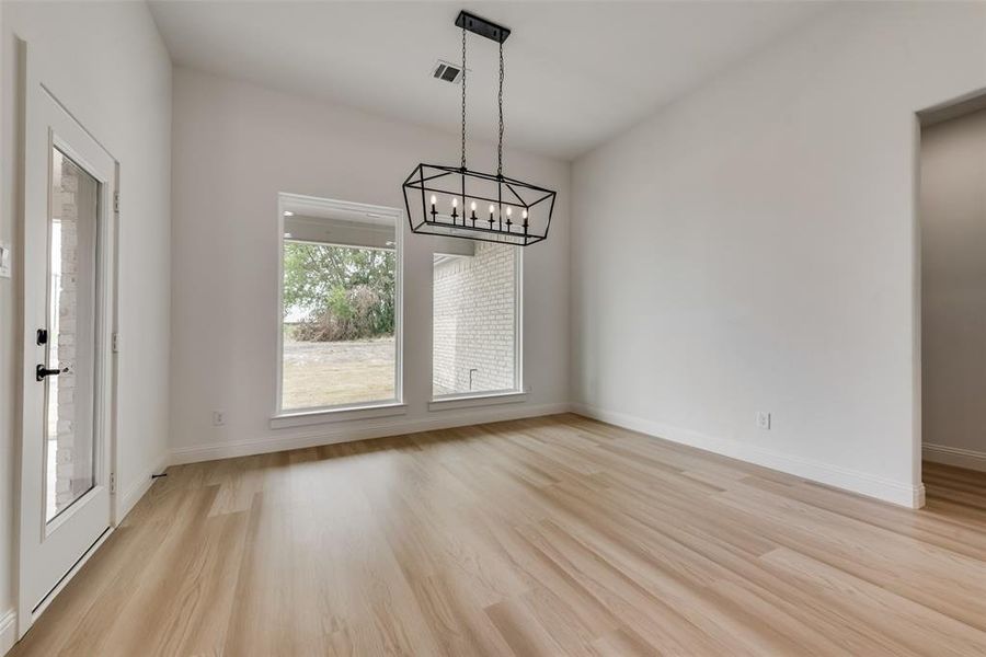Unfurnished dining area with an inviting chandelier and light wood-type flooring