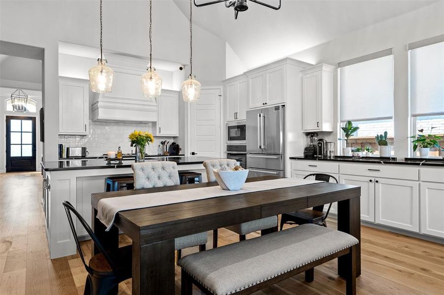 Kitchen featuring stainless steel appliances, white cabinets, light hardwood / wood-style floors, and tasteful backsplash