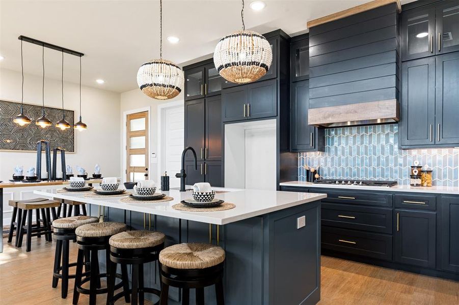 Kitchen featuring light hardwood / wood-style floors, a center island with sink, and pendant lighting