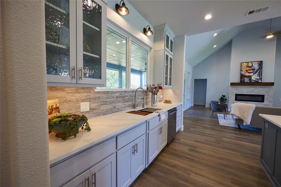 Kitchen featuring lofted ceiling, dark hardwood / wood-style flooring, backsplash, a stone fireplace, and sink