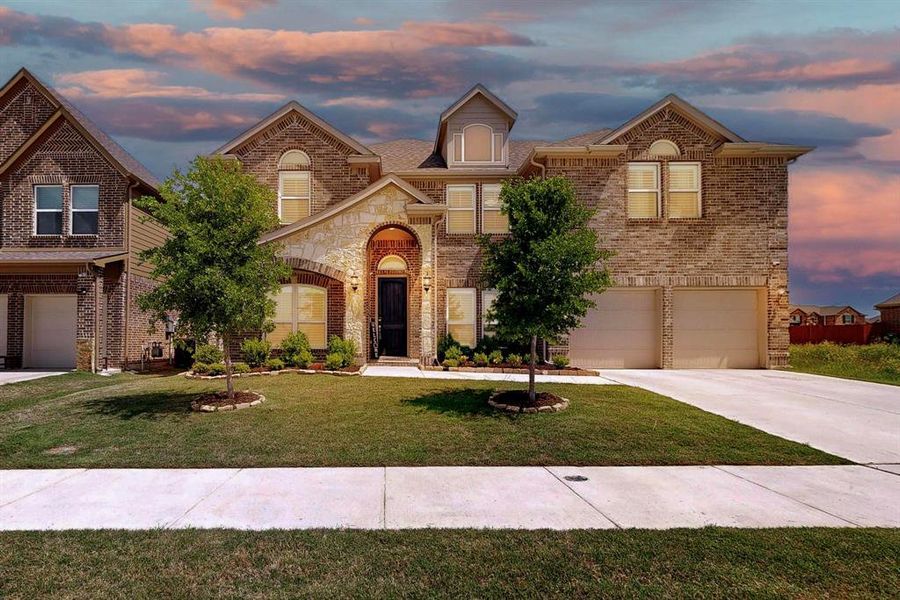 View of front of house featuring a lawn and a garage