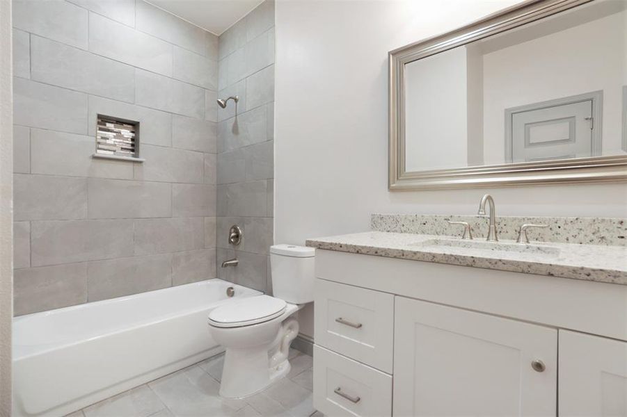 Full bathroom featuring tile floors, tiled shower / bath combo, vanity, and toilet