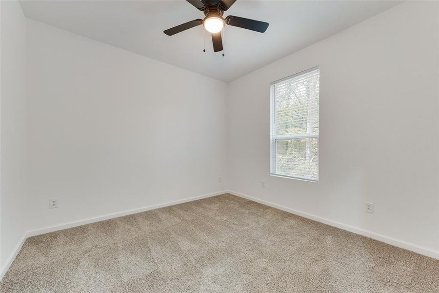 Carpeted empty room featuring ceiling fan