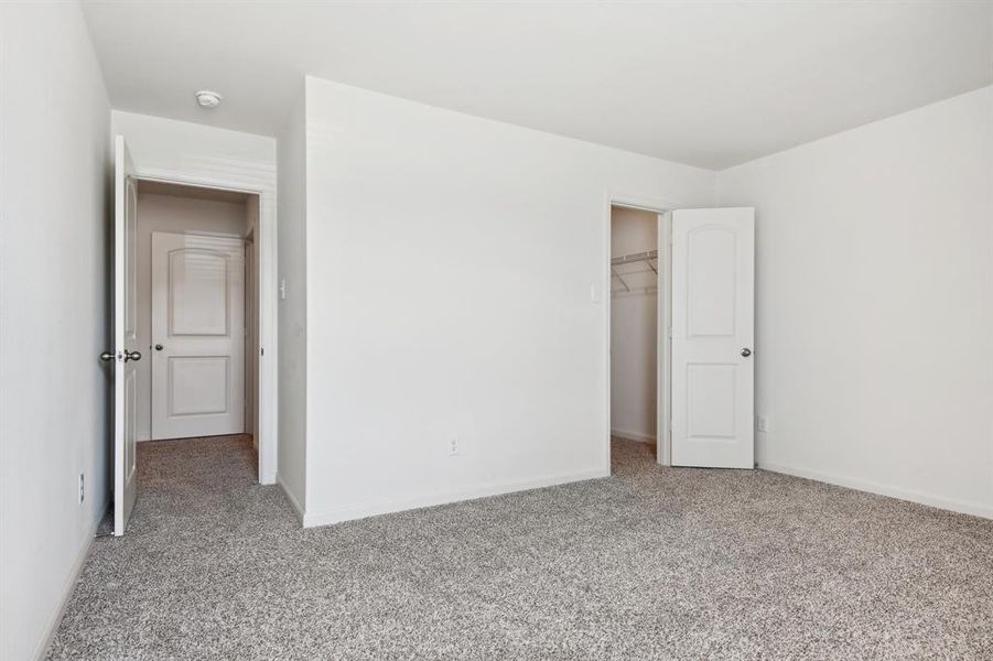 Unfurnished bedroom featuring light carpet, a closet, and a spacious closet