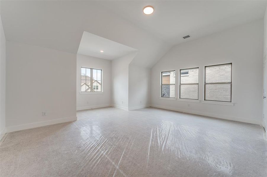 Empty room with light carpet and vaulted ceiling