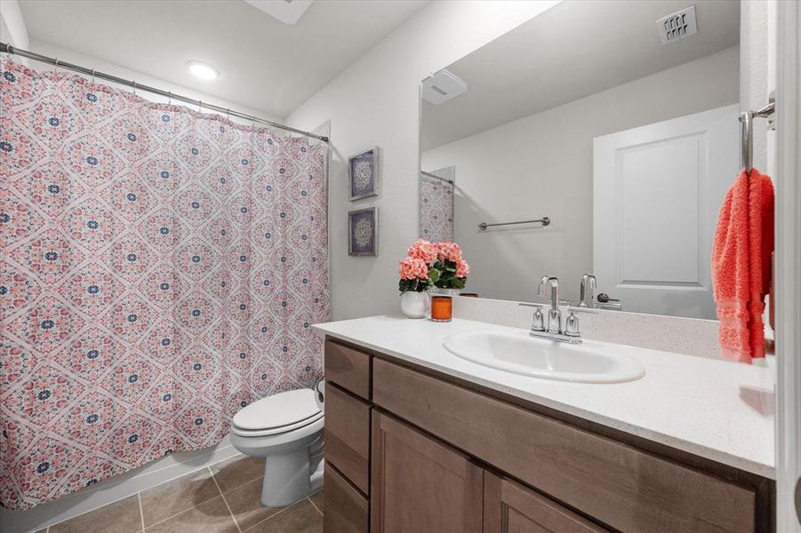 Bathroom featuring vanity, toilet, curtained shower, and tile patterned flooring