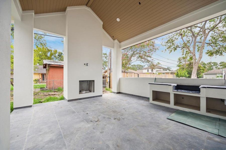 The outdoor kitchen is located in this spacious covered patio with vault ceiling making the best space for dining el fresco and relaxing and enjoying backyard fun.  Whether beautiful green space, a pool or play space, you will enjoy hours in this backyard!  The entire backyard is not pictured due to debris during the time of photography.  Come and check it out!  Photo as of 9/3/2024