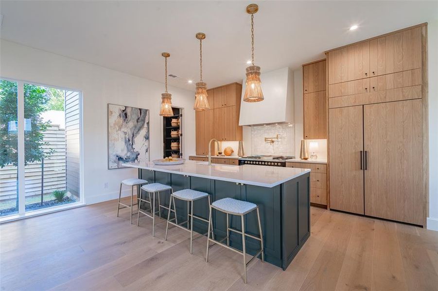 Kitchen with light hardwood / wood-style floors, light brown cabinetry, and a kitchen island with sink