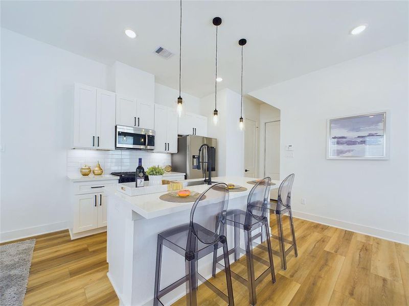 Contemporary kitchen with soft-close cabinet doors and drawers, black & stainless-steel appliances, & quartz countertops