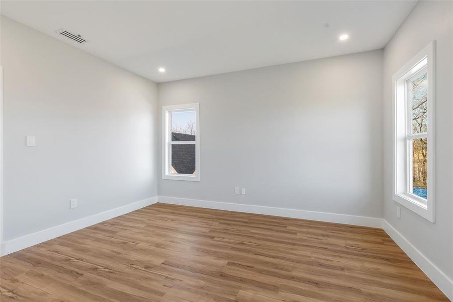 Empty room featuring light wood-type flooring and plenty of natural light