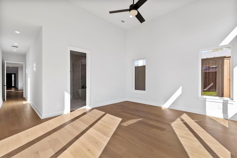 Empty room with hardwood / wood-style flooring, ceiling fan, and a towering ceiling