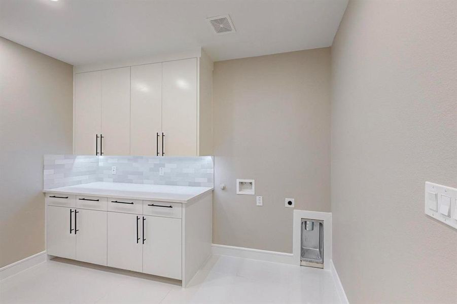 Washroom featuring cabinets, hookup for an electric dryer, washer hookup, and light tile patterned floors