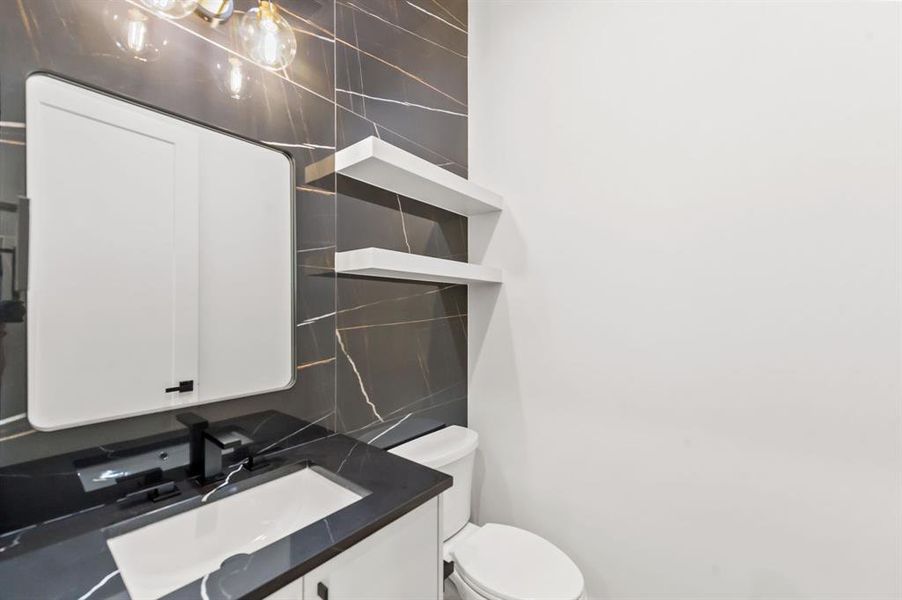 Half Bathroom featuring backsplash, vanity, and toilet