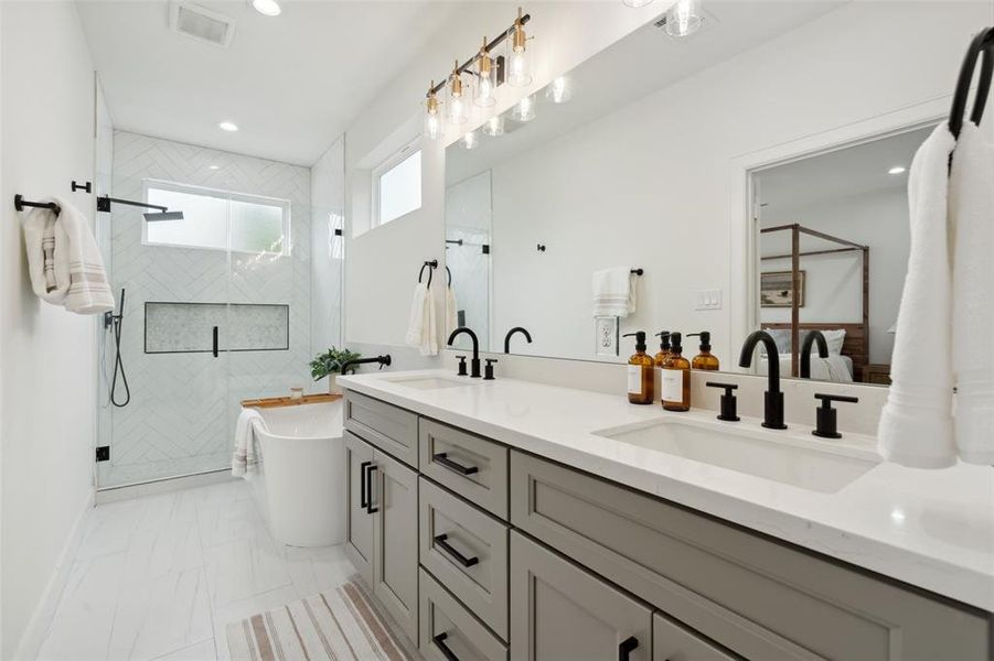 A lavish bathroom boasting his and hers sinks, a spacious soaking tub, and a sleek frameless glass shower. This space harmonizes functionality and style, offering an escape within the comfort of your own home.