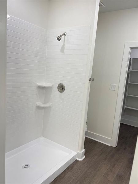 Bathroom with a tile shower, hardwood / wood-style flooring, and toilet