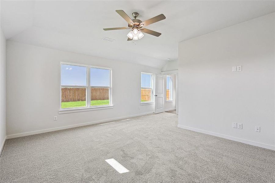 Spare room featuring ceiling fan, vaulted ceiling, and light colored carpet