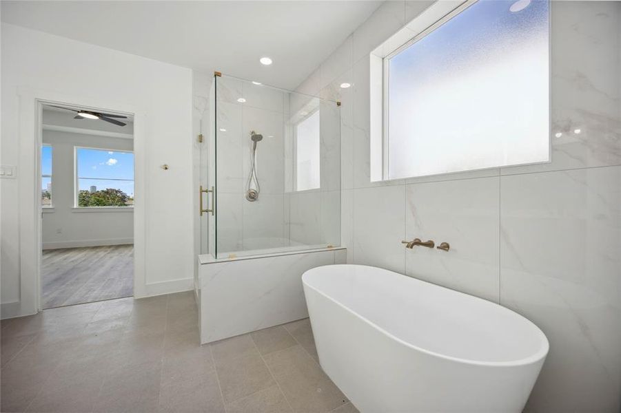 The primary bathroom features a freestanding bathtub, a glass-enclosed shower, and sleek tile. Enjoy added privacy and natural light coming in from a frosted window!