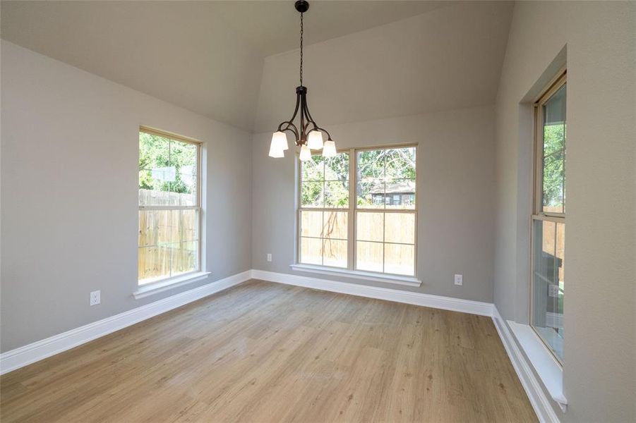 Unfurnished dining area featuring vaulted ceiling, light wood-type flooring, and plenty of natural light