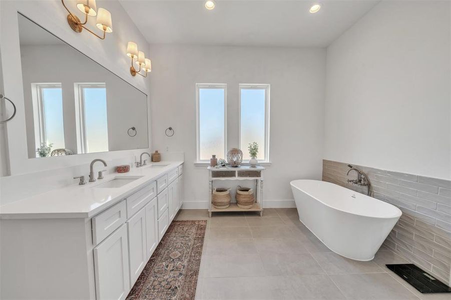 Primary Bathroom with a tub to relax in, tile patterned floors, vanity, and tile walls