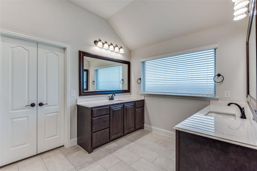 Bathroom with tile patterned flooring, vaulted ceiling, and vanity