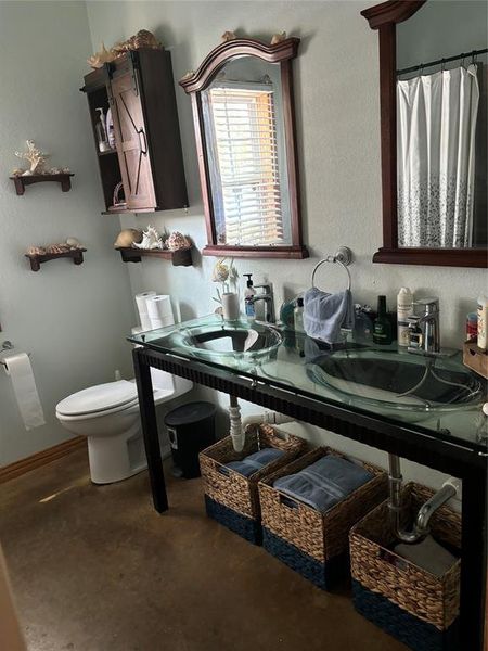 Bathroom with toilet, concrete floors, and vanity