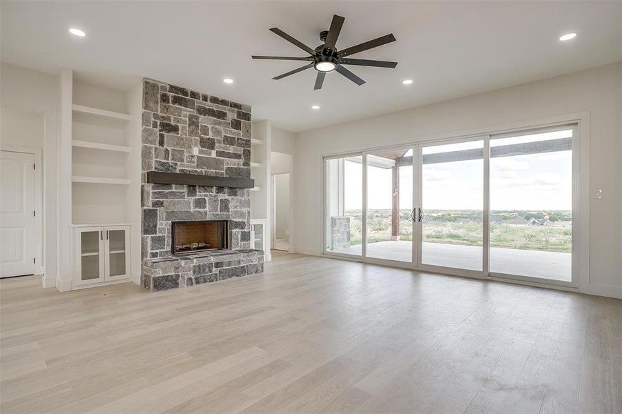 Unfurnished living room with a healthy amount of sunlight, ceiling fan, and a stone fireplace