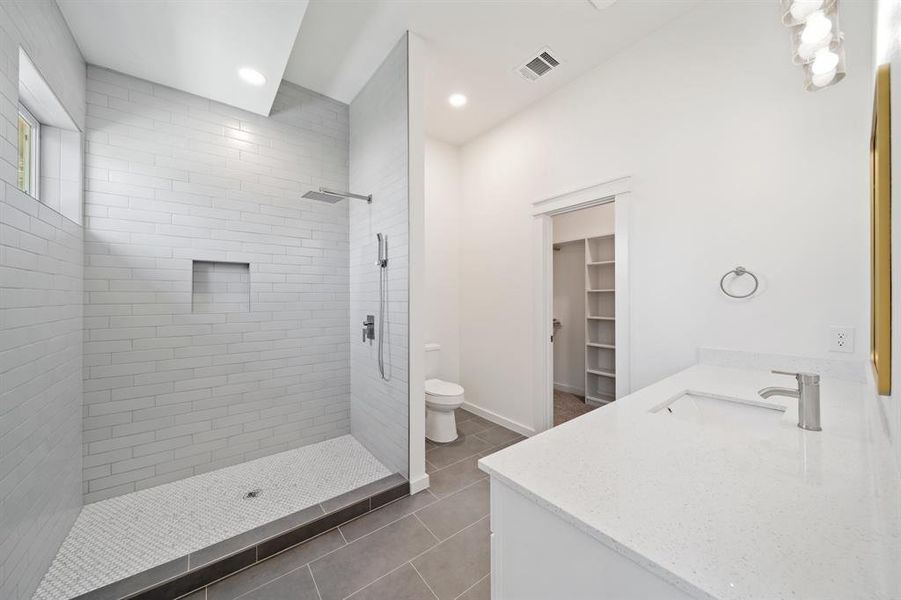 Bathroom with tile patterned flooring, toilet, vanity, and a tile shower