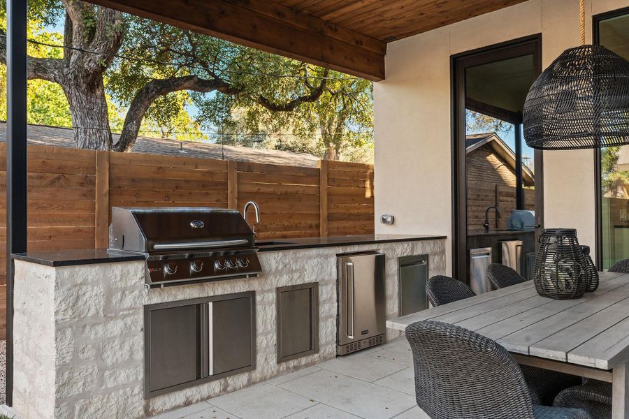 The fully equipped outdoor kitchen has plenty of storage, a 32" grill, a refrigerator, a trash pullout - all set in a matching masonry peninsula topped with a durable black granite countertop. A swing door connects the outdoor kitchen to the indoor kitchen - a must!