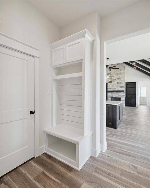 Mudroom with a fireplace, beamed ceiling, light hardwood / wood-style flooring, and ceiling fan