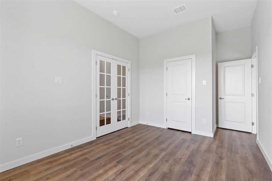 Unfurnished bedroom featuring french doors and dark hardwood / wood-style flooring