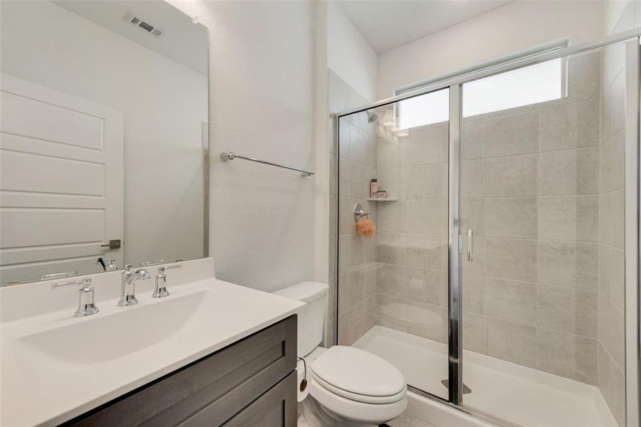 Bathroom featuring vanity, toilet, and a shower with shower door