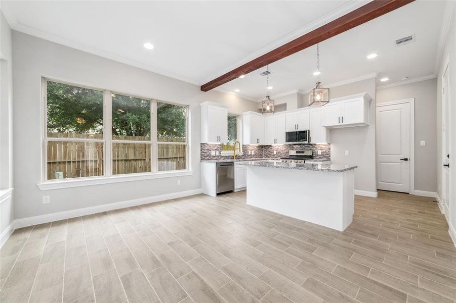 Experience seamless indoor-outdoor dining in this elegant breakfast room/dining room, adjacent to the kitchen, featuring sleek ceramic tile flooring and expansive windows that frame views of the inviting patio.