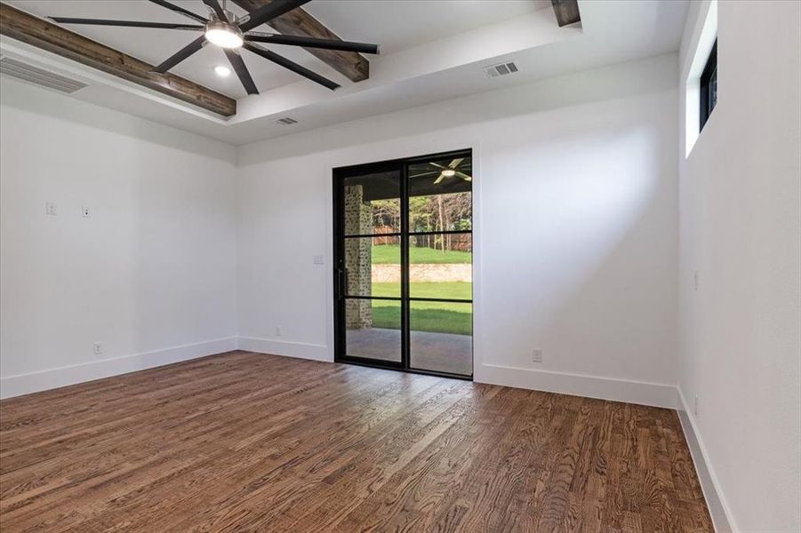 Unfurnished room with beamed ceiling, dark hardwood / wood-style floors, ceiling fan, and a raised ceiling