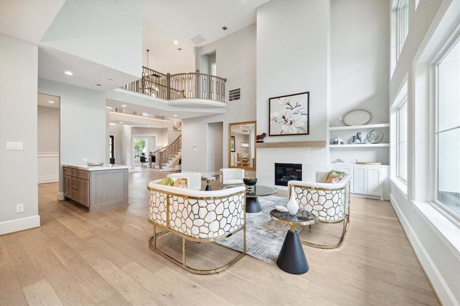 Another gorgeous view of this spacious, open-concept living area with high ceilings and ample natural light. It features a gourmet island kitchen with seating for 4-5 chairs.  Stunning view of the upper-level Juliet balcony, creating a luxurious and airy atmosphere.