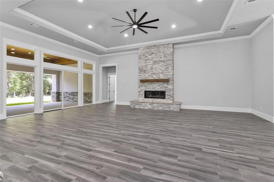 The Family Room features a modern inset gas fireplace with stone running all the way to the incredibly high ceilings, a tray ceiling with an oversized ceiling fan, beautiful crown moldings, along with two shielded CAT6A (Ethernet/Data) and shielded coaxial (TV) cables.